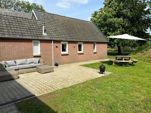 a patio with a couch and a table and an umbrella at Knus huisje met palletkachel in Tiendeveen