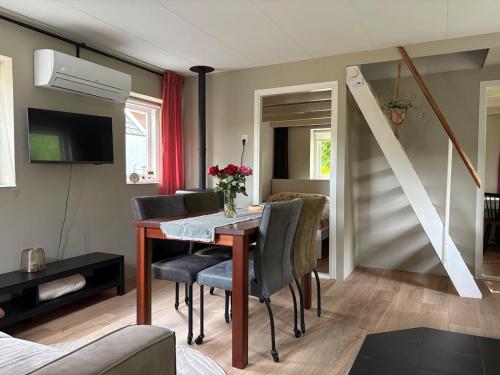 a living room with a dining room table with chairs at Knus huisje met palletkachel in Tiendeveen