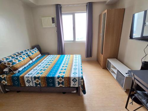a bedroom with a bed and a tv and a window at SM Cebu City Sunvida Tower Condominium in Cebu City