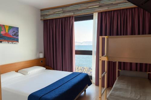 a bedroom with a bed and a large window at Casa Rossa 1888 in Torre del Greco