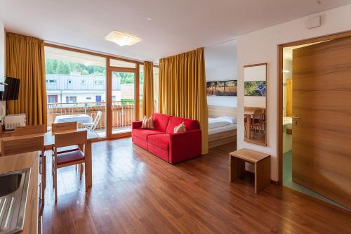 a living room with a red couch and a bedroom at Residence Aichner in Brunico