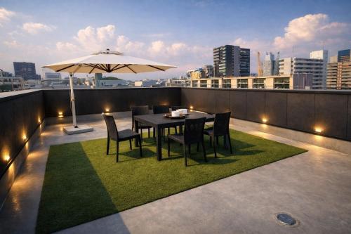 a table and chairs on a balcony with an umbrella at 大阪梅田西3a in Osaka