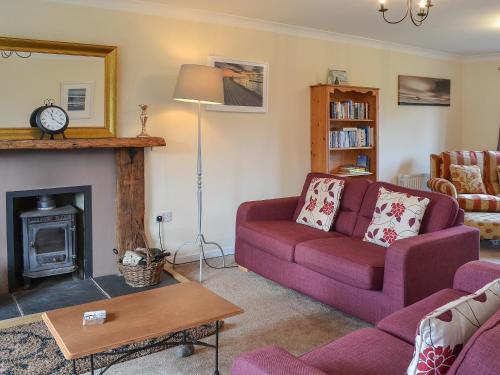 a living room with a purple couch and a fireplace at Sand Castles in Seahouses