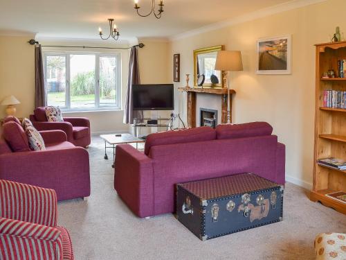 a living room with purple couches and a tv at Sand Castles in Seahouses