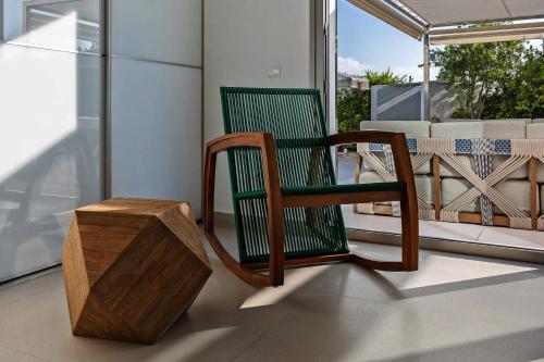a green rocking chair and a wooden box on a porch at Super views in Mykonos in Psarou