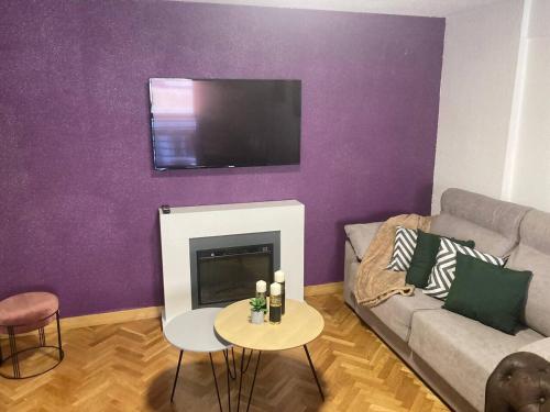 a living room with a couch and a tv on a purple wall at Dúplex céntrico La Ranita Salmantina in Salamanca