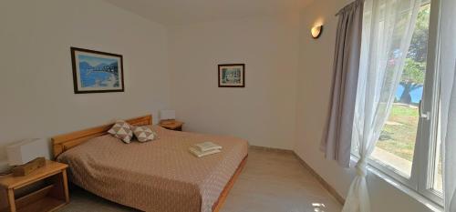 a bedroom with a bed and a large window at Beach front with Swimming pool, Illyria Resort Apt 101 in Milna