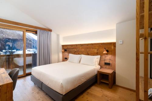 a hotel room with a bed and a large window at Breithorn Lodge in Champoluc