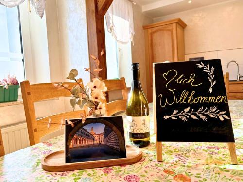 a bottle of wine and a picture on a table at Ferienhaus Landeskrone für 10 Personen mit Sauna, Terrasse, inkl Parkplatz in Dresden in Dresden