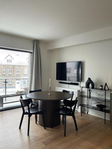 a living room with a table and chairs and a tv at Central nyrenoveret lejlighed i Aalborg in Aalborg