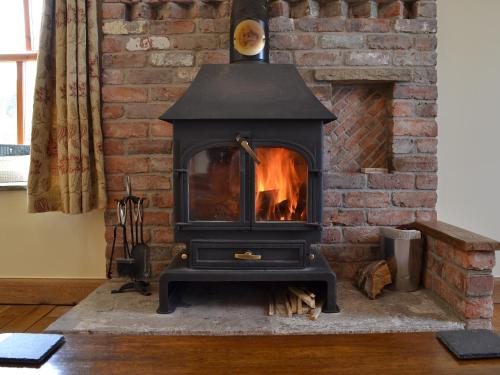 a stove in a room with a brick wall at Bings Farm House in Whaley Bridge