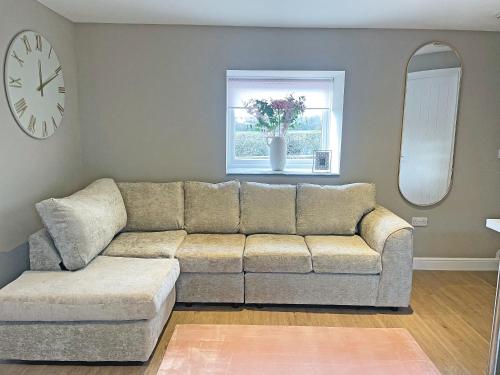 a living room with a couch and a clock at Pasture Barn in Barnard Castle