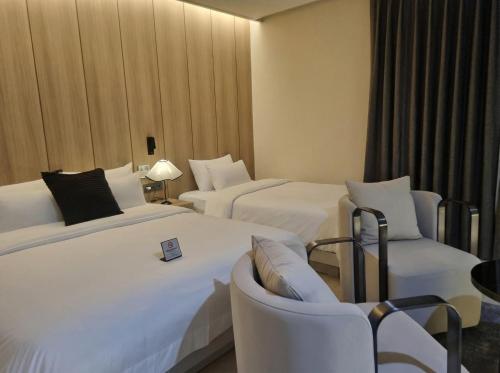 a hotel room with two beds and two chairs at Hotel Signature Gwangju in Gwangju