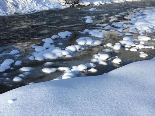 a river covered in snow with snow on the banks at Xenia Apartments in Kappl
