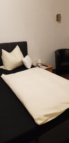 a bed with white sheets and pillows on it at Hotel Haus Schüppen in Wegberg