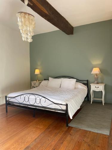 a bedroom with a bed and two tables and a chandelier at Guest House, Private Pool in LʼIsle-en-Dodon