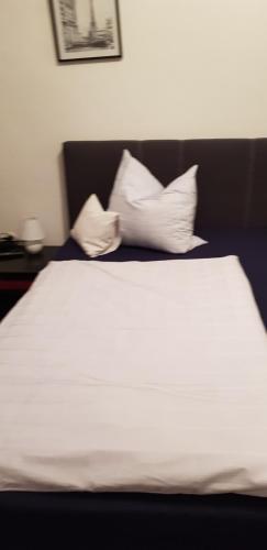 a bed with white sheets and pillows in a room at Hotel Haus Schüppen in Wegberg