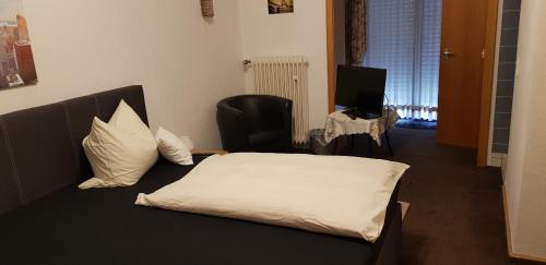 a bedroom with a bed and a chair and a television at Hotel Haus Schüppen in Wegberg