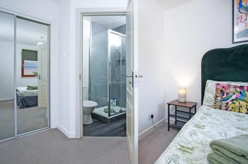 a bedroom with a glass door leading to a bathroom at 2Bed City Central East End Gem with Free Parking in Glasgow