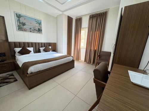 a bedroom with a bed and a desk in a room at Gokul Dham in Haridwār