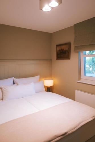a bedroom with a large white bed and a window at Sünn un See - Hortensienblick in Ahrenshoop
