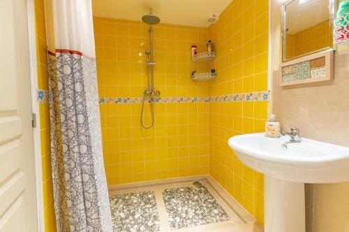 a yellow tiled bathroom with a shower and a sink at Private gîte with stunning views & shared pool in Laussou