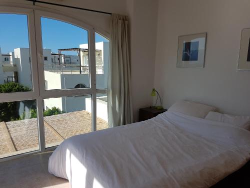 a bedroom with a white bed and a balcony at Aphrodite Beachfront Penthouse Apartment in Ghaziveran