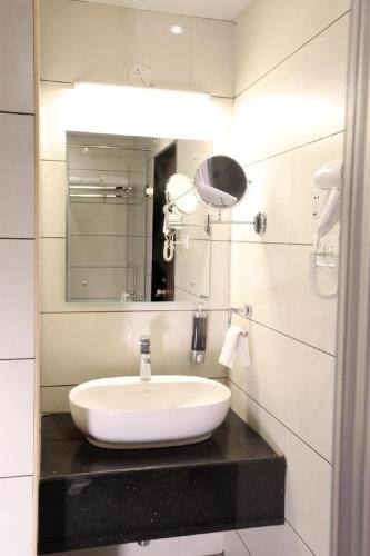 a bathroom with a white sink and a mirror at The White Pearl Suites in Bangalore