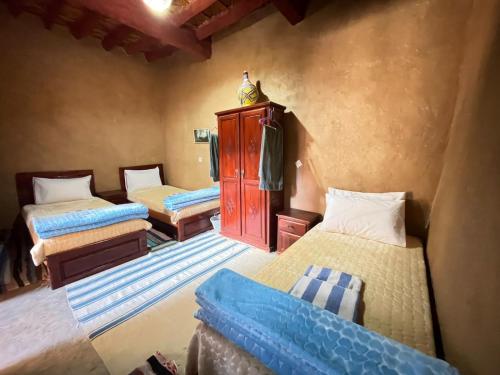 a room with three beds and a cabinet in it at MAISON D'HOTE DAR IMRANE in Tatta