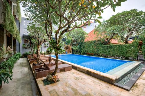 a swimming pool with a tree and benches around it at D Sarian Seminyak in Seminyak