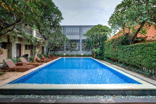 a swimming pool in a garden with chairs and trees at D Sarian Seminyak in Seminyak