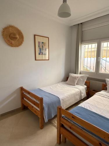 two beds in a room with two windows at Maison casa bloom - La marsa in Bin Rhilouf
