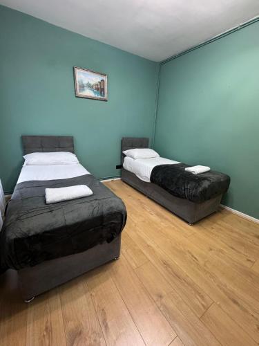 two beds in a room with blue walls and wooden floors at Euston Central Apartment in London