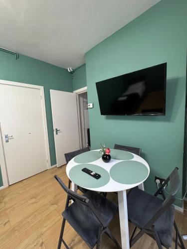 a room with a table with chairs and a tv on the wall at Euston Central Apartment in London