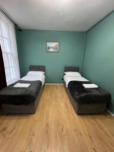 two beds in a room with blue walls and wooden floors at Euston Central Apartment in London