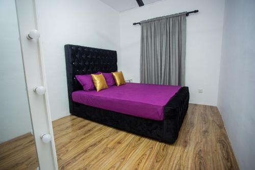 a bedroom with a bed with purple sheets and yellow pillows at Villa Ceilaoo in Galle