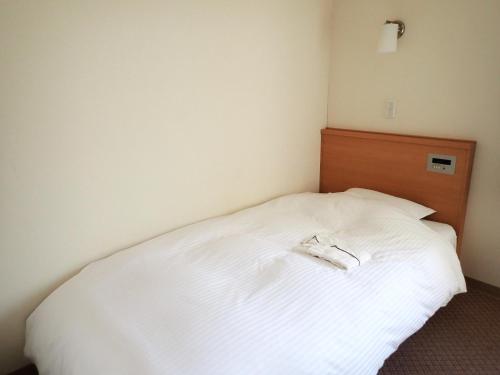a bedroom with a white bed with a wooden headboard at Hotel Tetora Higashimuroran - Vacation STAY 75821v in Muroran