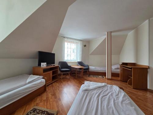 a bedroom with two beds and a desk with a tv at Apartamenty Cafe Wielbark in Wielbark