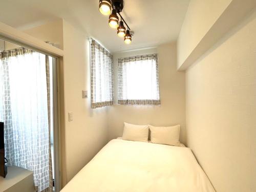 a small bedroom with a bed with two windows at The Grand Win in Fukuoka