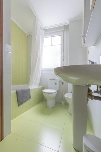 a bathroom with a sink and a toilet and a window at Gibaja Apartmento con Jardin in Gibaja