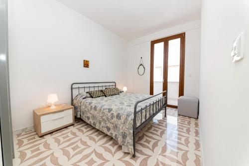 a white bedroom with a bed and a night stand at Il Bacio del Sole - San Foca in San Foca