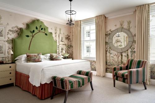 a bedroom with a large bed and two chairs at Haymarket Hotel, Firmdale Hotels in London