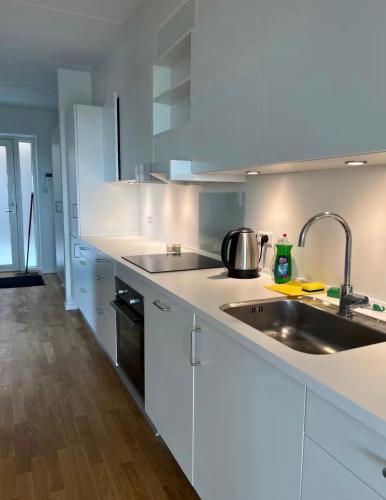 a kitchen with white cabinets and a sink at Beach View Apartment in Vallensbæk in Vallensbæk