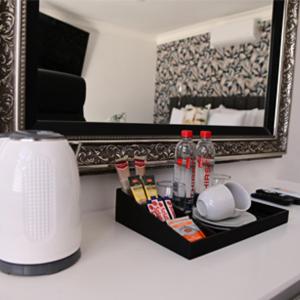 a bathroom counter with a mirror and a shelf with drinks at His Grace Eagles Guesthouse in Bloemfontein