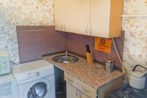 a small kitchen with a sink and a washing machine at ALLiS-HALL Apartament at Karla Libkknekhta 16 in Yekaterinburg
