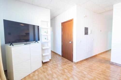 a living room with a large television and a wooden door at Edificio Prieto VIV 2B in Puerto del Rosario