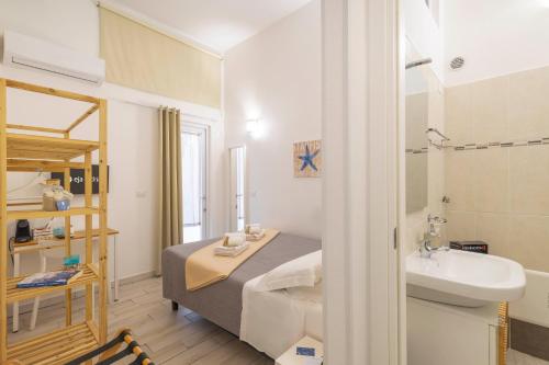 a small room with a bed and a sink and a bathroom at Approdo Rooms - Eja Sardinia in Cagliari
