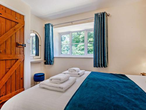 a bedroom with a bed with blue curtains and a window at 3 Bed in Dorchester oc-92414 in Frome Vauchurch