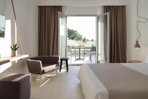a bedroom with a bed and a chair and a balcony at Livin Mykonos Hotel - Adults Only by Mr and Mrs White in Mikonos