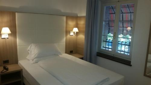 a white bed in a room with a window at La Locanda in Aviano